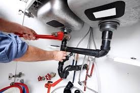 Licensed plumber fixing leaking pipe under kitchen sink in Long Island home